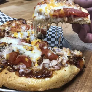 a person taking a slice of pizza