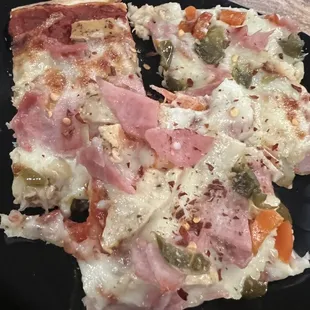 two slices of pizza on a black plate