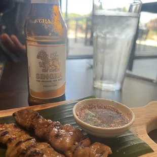 a plate of skewered food and a bottle of beer