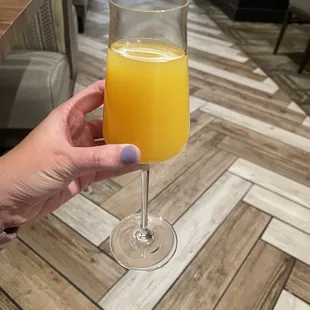 a person holding a glass of orange juice