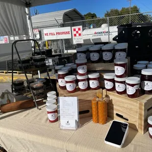 a table with jars of jams and a phone