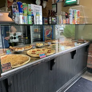 Display at entrance by the cashier  with options for pizza by the slice.