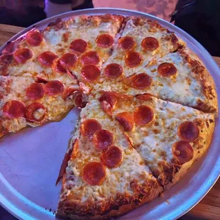 a pepperoni pizza with a slice taken out of it