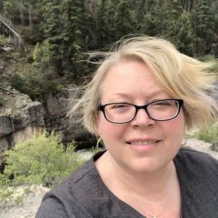 a woman wearing glasses and a gray shirt