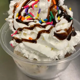 a cup of ice cream with chocolate sauce and sprinkles