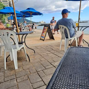 a man sitting at a table with blue umbrellas