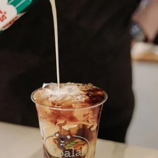 a person pouring milk into a cup