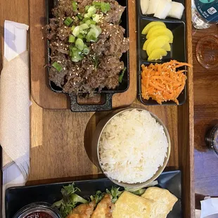 Beef bulgogi plate with white rice, pickled radish, carrots, tofu, and veggie dumplings