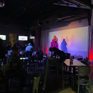 a woman on stage in a brightly lit room