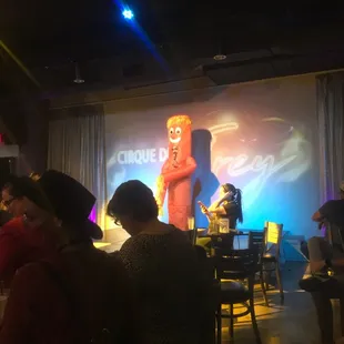 people sitting at tables in front of a projector screen