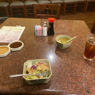 a table with a bowl of salad and a bowl of soup