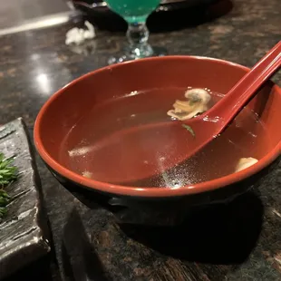 a bowl of soup with a red spoon
