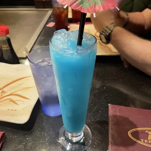 a blue drink with a pink umbrella
