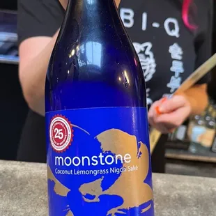 a woman holding a bottle of moon stone