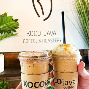 two cups of coffee in front of a sign