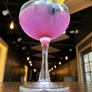 a pink cocktail with a lemon garnish