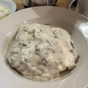 Sausage gravy and biscuits with an over easy fried egg on the side.