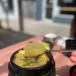 a person holding a spoon with a piece of food in it