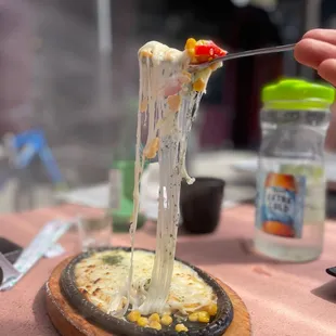 a hand holding a fork with a piece of pizza on it