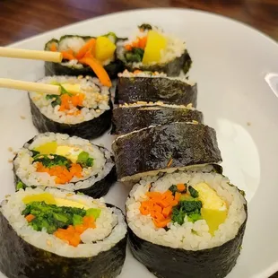 a plate of sushi with chopsticks