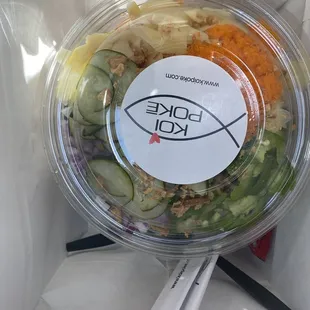 a salad in a plastic container with chopsticks