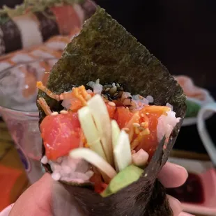  a hand holding a piece of sushi