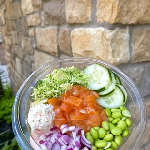 a hand holding a poke poke bowl