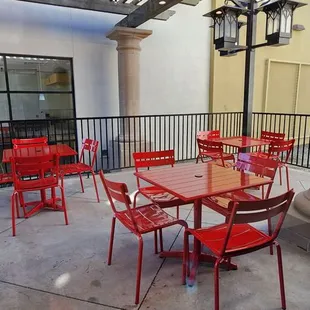 a patio with red chairs and tables