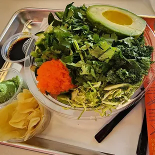 a salad with avocado, lettuce, carrots, and noodles