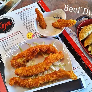 a plate of fried dumplings and a plate of fried chicken