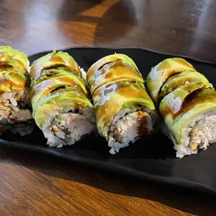 four rolls of sushi on a black plate