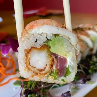 a close up of a sushi roll on a plate with chopsticks