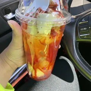 a hand holding a plastic cup of food