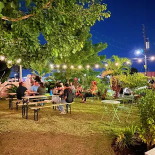 a group of people sitting at tables in a park