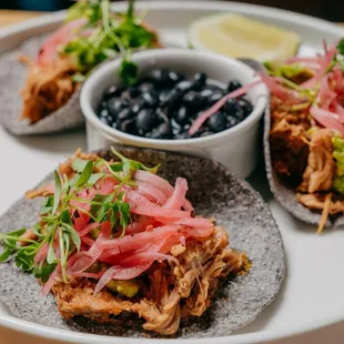 a plate of tacos and a bowl of black beans