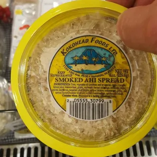 a hand holding a container of kokohead spread