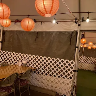 All outdoor seating in a white tent with heat lamps and lanterns