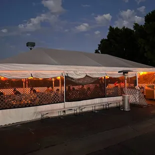a white tent with white tarps and lights