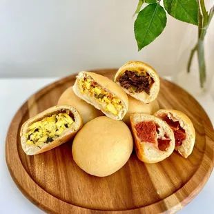 a pile of bread rolls on a wooden plate