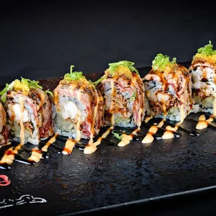 a long row of sushi rolls on a black plate