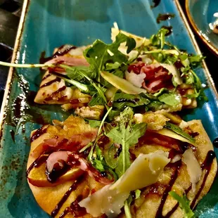 Chef&apos;s Kiss! Flat bread with fig jam, gorgonzola, prosciutto, apple and pear slices. Topped with arugula and a balsamic drizzle.