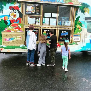 a group of kids standing in front of a food truck