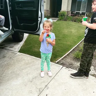 a young boy and girl standing in front of a car