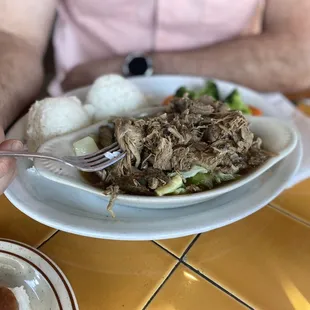 a plate of pulled pork with rice and vegetables