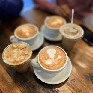 four cups of coffee on a wooden table