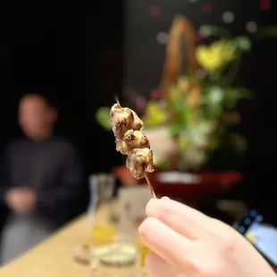 a person holding a skewer of food