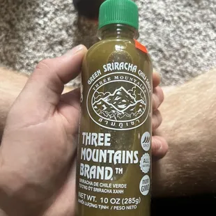 a hand holding a bottle of three mountains brand
