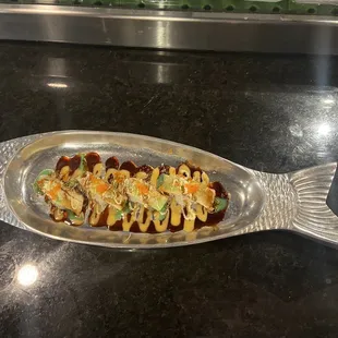 a fish shaped platter with sushi on it