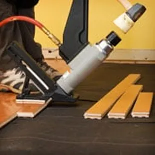a person using a nail gun to nail a hardwood floor