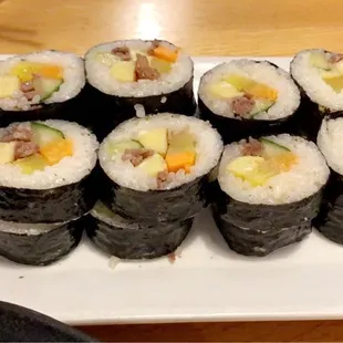 a plate of sushi rolls with chopsticks